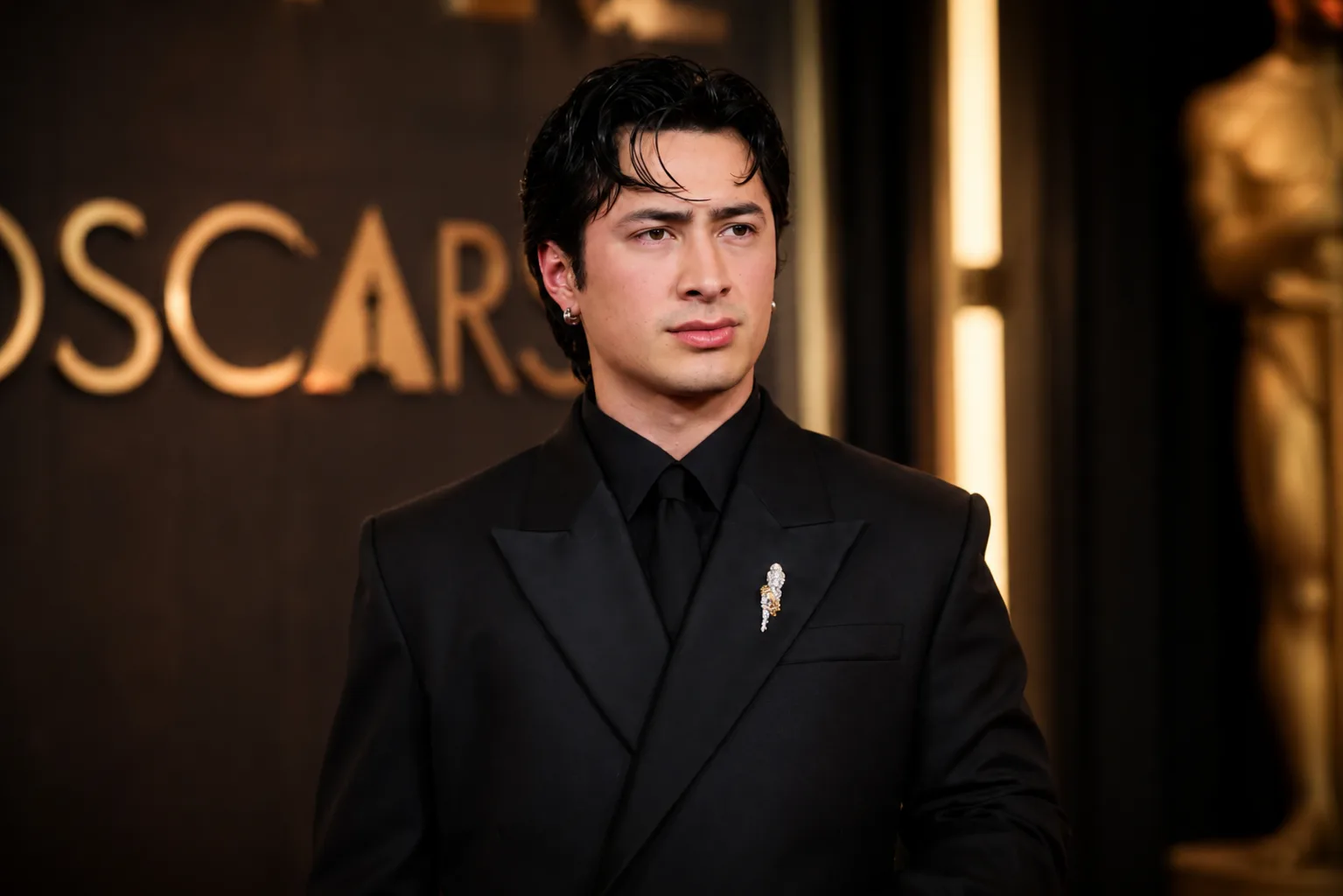 Hudson Williams poses on the Oscars red carpet wearing a black tuxedo during a public appearance.