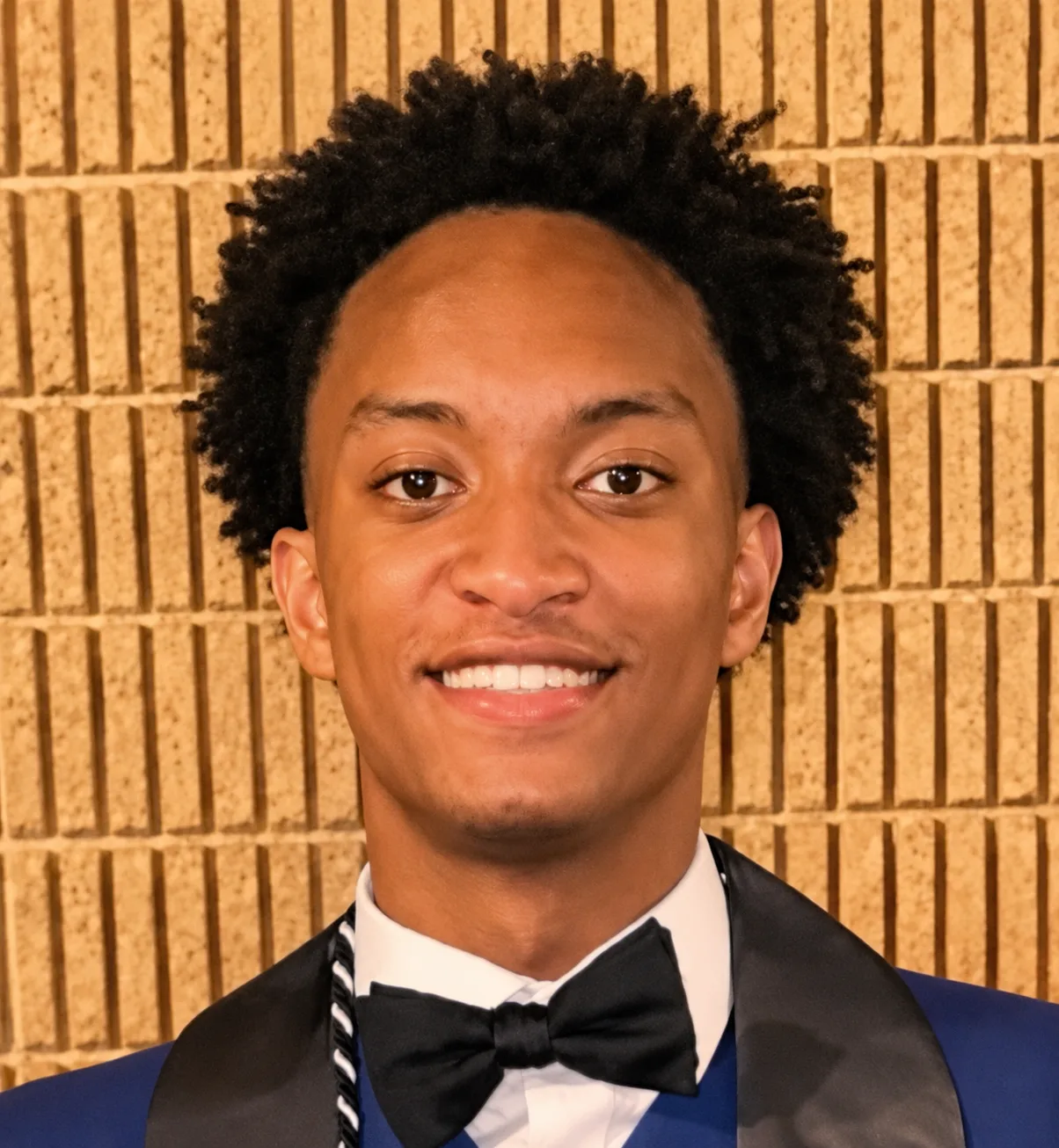 Portrait of Nolan Wells wearing a tuxedo and bow tie in a formal graduation-style photograph.